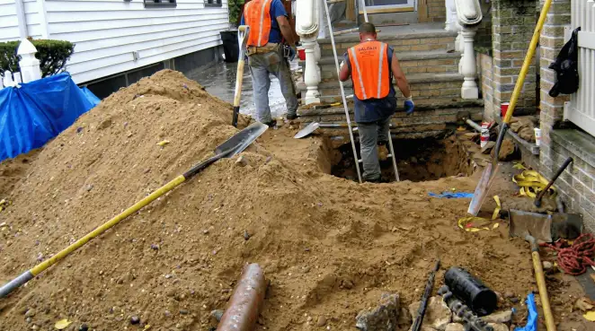 Contractors performing foundation protection and exterior drainage excavation near residential home steps in Columbus, GA